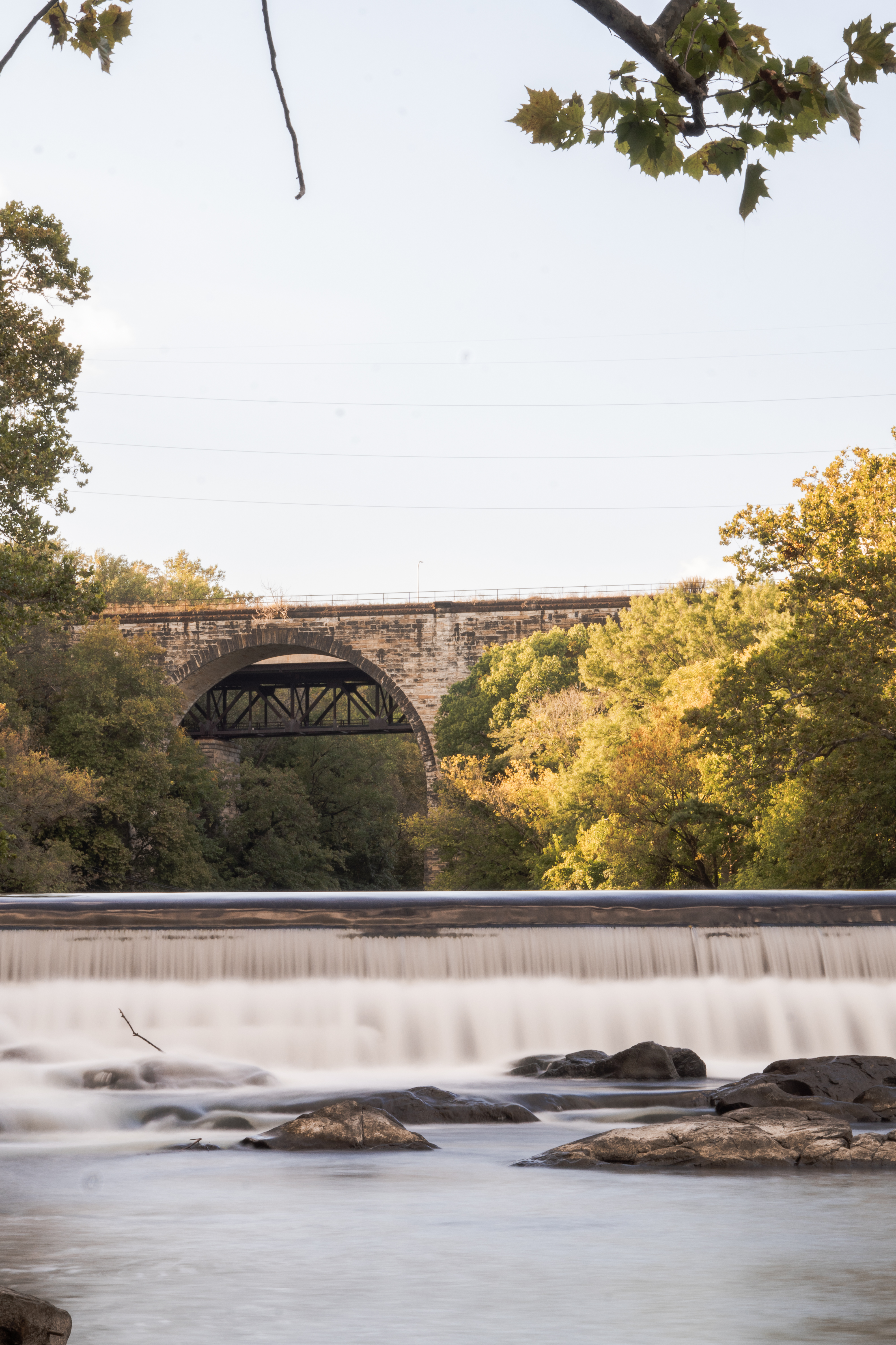 Scenic bridge over river surrounded by lush greenery and dramatic sky